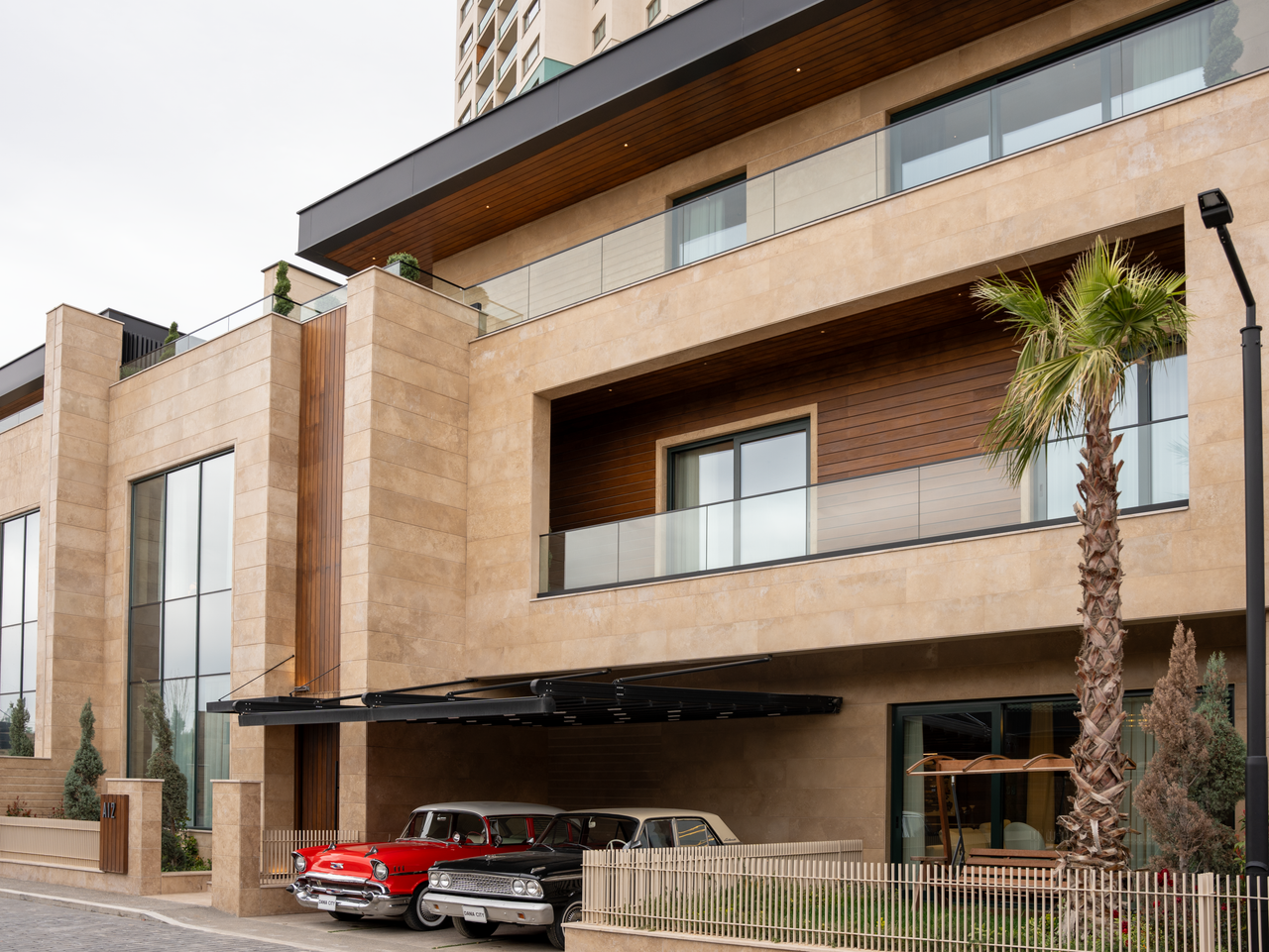 our-story Exterior view of a modern luxury building with vintage cars parked under a sleek balcony.